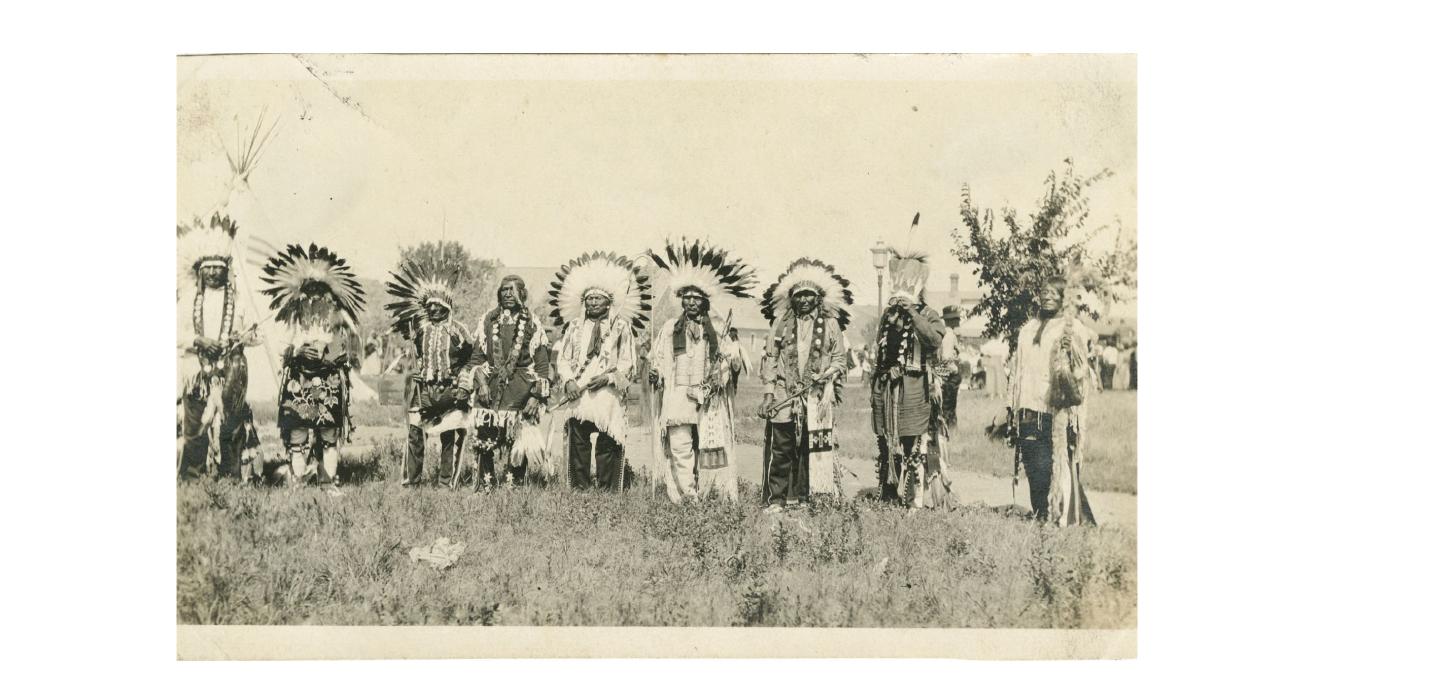Nine Native American men standing in a line at a powwow event